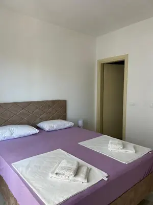 two beds in a room with purple sheets and pillows at Apart Hotel White Pearl in Bar