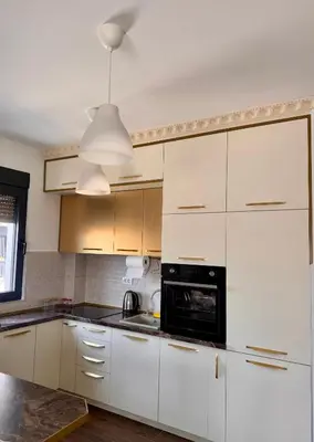 a kitchen with white cabinets and a black appliance at Lovely Modern LUX flat near to the center in Podgorica