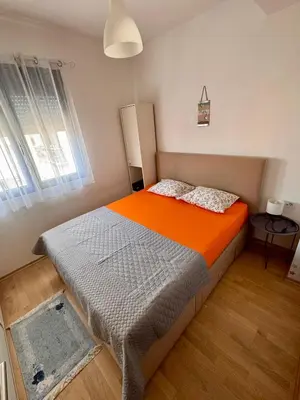 a bedroom with a large bed with an orange blanket at Lovely Modern LUX flat near to the center in Podgorica