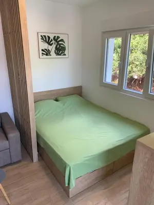 a small bedroom with a green bed in a room at Cozy apartment in The Old Bakery Residences in Budva