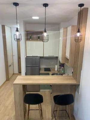 a kitchen with two bar stools and two lights at Cozy apartment in The Old Bakery Residences in Budva