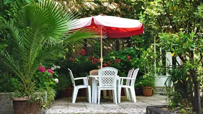 a table and chairs under an umbrella in a garden at Villa Stanivukovic in Budva