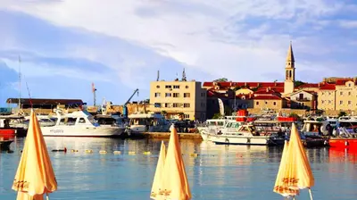two yellow umbrellas in the water in a harbor with boats at Villa Stanivukovic in Budva