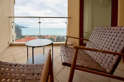 a balcony with a table and chairs and a large window at BigMontenegro Belveder in Becici