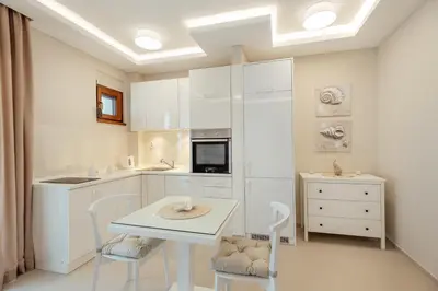 a kitchen with white cabinets and a table and chairs at Apartments Dabinovic in Kotor