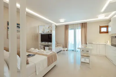 a white room with a bed and a kitchen at Apartments Dabinovic in Kotor