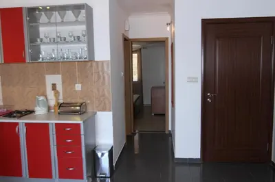 a kitchen with red and white cabinets and a door at Apartments Muhar in Sveti Stefan