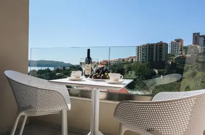 a table with a bottle of wine and two chairs at Status-M Apartments 102 in Becici