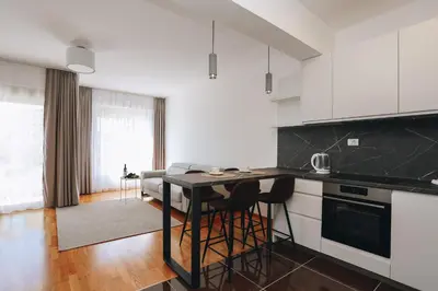 a kitchen with white cabinets and a table and chairs at Status-M Apartments 102 in Becici