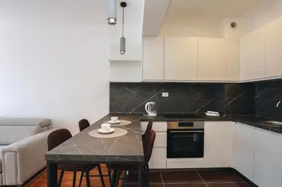 a kitchen with white cabinets and a table with chairs at Status-M Apartments 102 in Becici