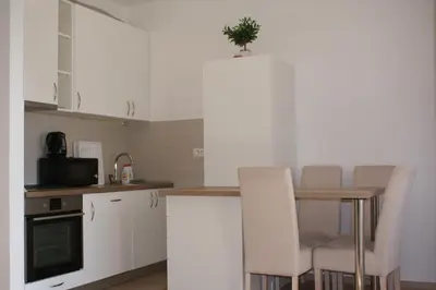 a kitchen with white cabinets and a table with chairs at Engora 2 in Petrovac na Moru