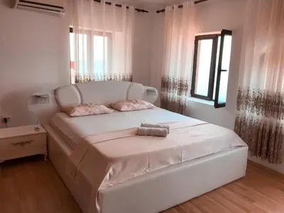 a white bed in a white bedroom with a window at Guest house Naser in Ulcinj
