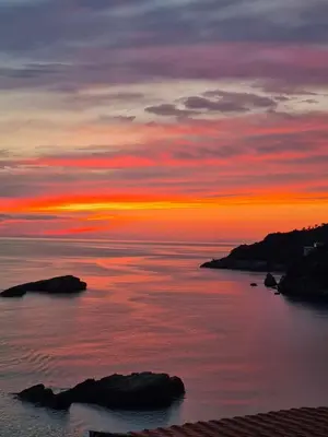 a sunset over the ocean with rocks in the water at Guest house Naser in Ulcinj