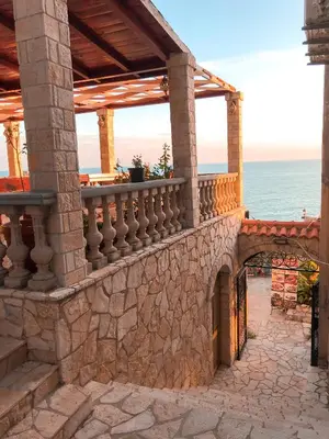 a stone building with a balcony overlooking the ocean at Guest house Naser in Ulcinj