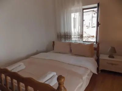 a bedroom with a bed with white sheets and a window at Guest house Naser in Ulcinj