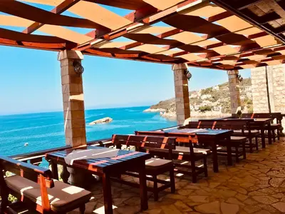 a row of tables and chairs with the ocean in the background at Guest house Naser in Ulcinj
