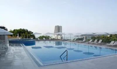 a large swimming pool with chairs and a building in the background at Status-M apartments 98 in Becici