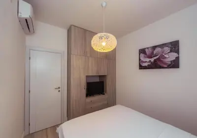 a bedroom with a white bed and a television at Engora 5 in Petrovac na Moru
