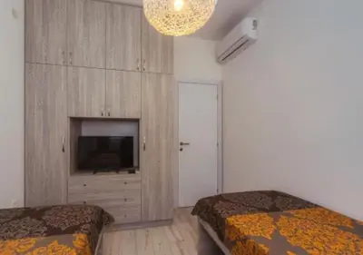 a bedroom with two beds and a television and a chandelier at Engora 5 in Petrovac na Moru
