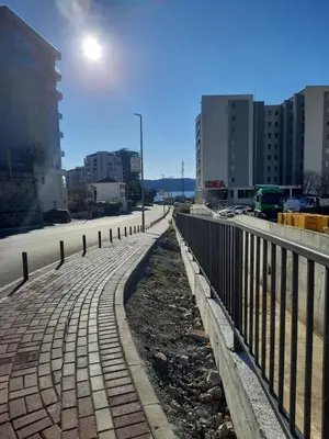 a brick sidewalk next to a fence in a city at Marina Apartment in Becici