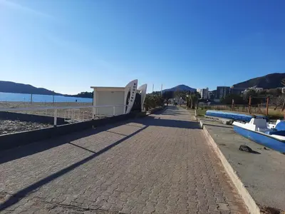 a brick sidewalk next to a beach with boats on it at Marina Apartment in Becici
