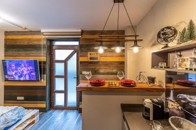 a room with a bar with wine glasses and a tv at Apartman_PidžuN in Cetinje