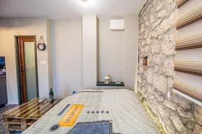 a bedroom with a bed with a stone wall at Apartman_PidžuN in Cetinje