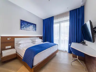 a bedroom with a bed and a desk with a computer at Hotel TQ Plaza in Budva