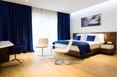 a bedroom with a bed with blue curtains and a desk at Hotel TQ Plaza in Budva
