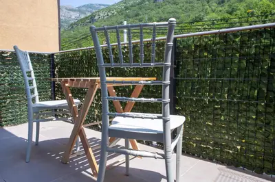 two chairs sitting next to a table on a balcony at Family Apartments Vukcevic in Čanj