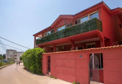 a red building with vegetation on top of it on a dirt road at Family Apartments Vukcevic in Čanj