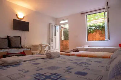 a bedroom with two beds and a window and a table at Family Apartments Vukcevic in Čanj