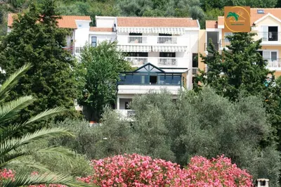 a building with trees and flowers in front of it at Villa Lutovac Budva in Budva