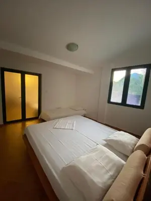 a large white bed in a room with two windows at Villa Lutovac Budva in Budva
