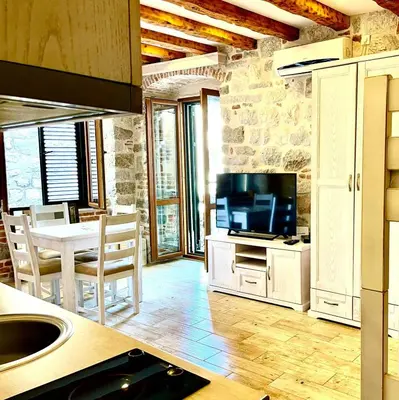 a kitchen and dining room with a television and a table at Apartaments Charlie Chaplin in Kotor