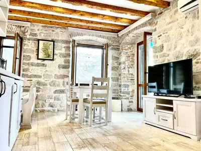 a living room with a table and a tv and a stone wall at Apartaments Charlie Chaplin in Kotor
