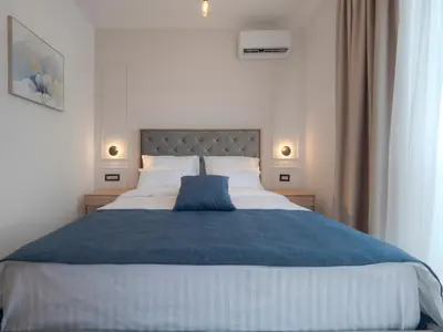 a bedroom with a large bed with a blue blanket at Hotel Idila Budva in Budva