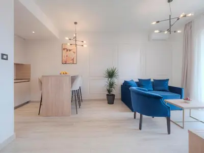 a living room with a blue couch and a table at Hotel Idila Budva in Budva