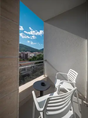 two white chairs and a table on a balcony at Hotel Idila Budva in Budva