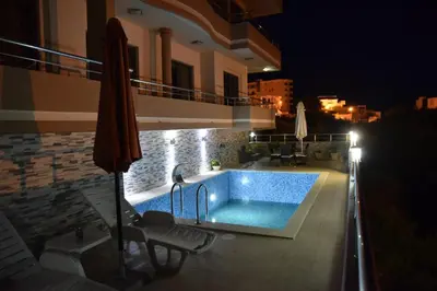 a swimming pool in front of a house at night at Guest House Evropa 2 in Ulcinj