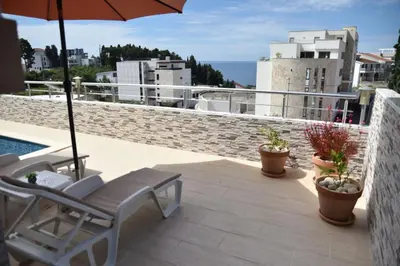 a patio with a chair and an umbrella on a roof at Guest House Evropa 2 in Ulcinj