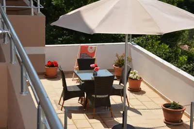 a table and chairs with an umbrella on a balcony at Guest House Evropa 2 in Ulcinj