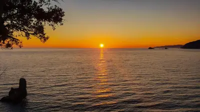 a sunset over the water with the sun setting at Apartments Viktorija in Petrovac na Moru