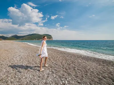 a woman in a white dress standing on a beach at Apartments Viktorija in Petrovac na Moru