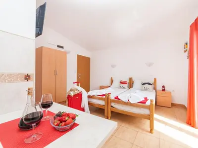 a room with a bed and a table with wine glasses at Apartments Viktorija in Petrovac na Moru