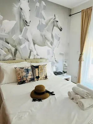a hat on a bed with a mural of horses at Apartment Juliette Budva in Budva