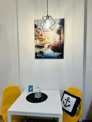 a white table with two yellow chairs and a painting at Apartment Juliette Budva in Budva