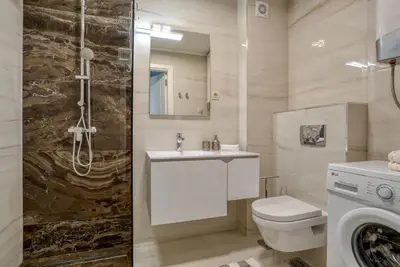 a bathroom with a toilet and a sink and a shower at Apt 