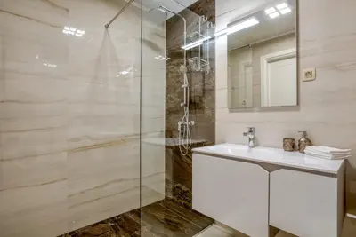 a bathroom with a glass shower and a sink at Apt 