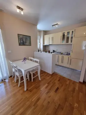 a kitchen and dining room with a white table and chairs at Sunny City - City Kvart in Podgorica